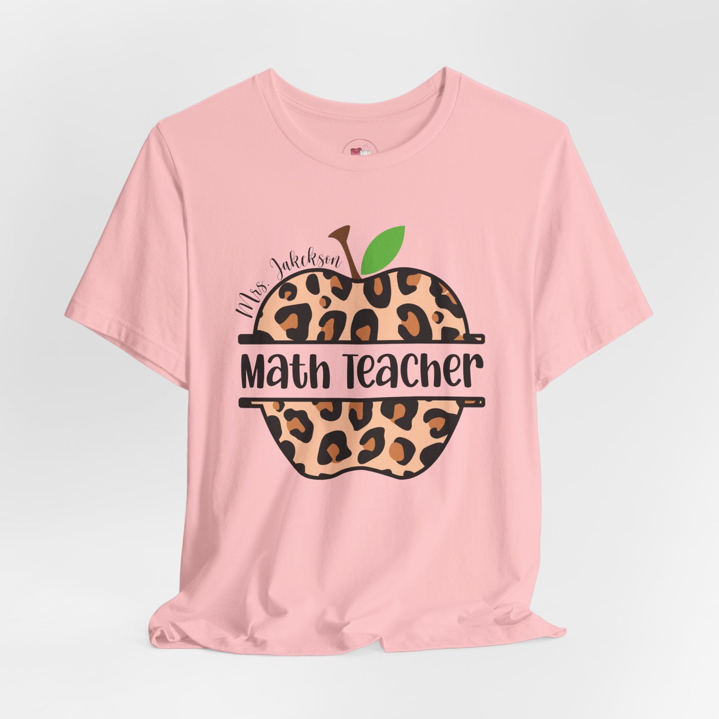 Pink t-shirt with leopard print apple design and text on a light gray background