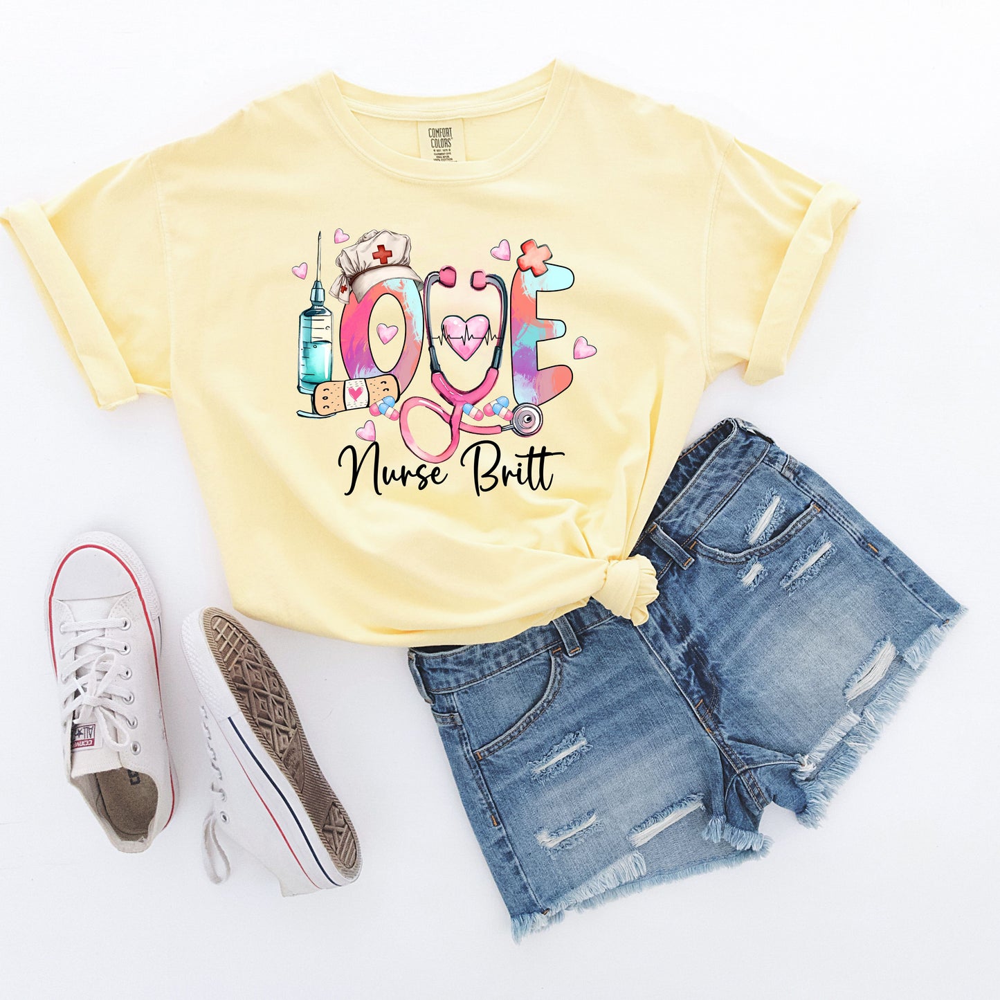 Yellow t-shirt with colorful 'LOVE' design featuring a stethoscope, syringe, and nurse's hat on a white background.