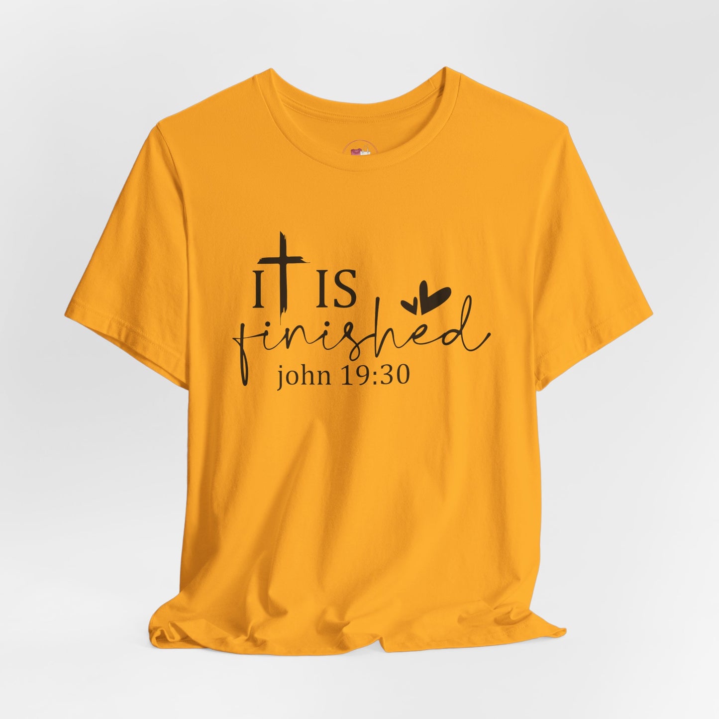 Gold t-shirt with 'It is finished' text and cross design on a white background, Bible scripture