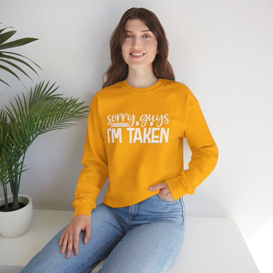 Woman wearing a yellow sweatshirt with 'sorry guys I'm taken' text, sitting indoors.