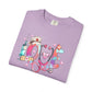Purple t-shirt with colorful 'LOVE' design featuring a stethoscope, syringe, and nurse's hat on a white background.