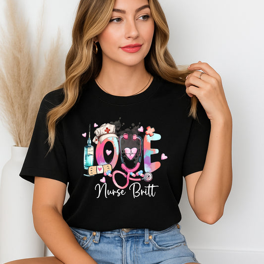 Black t-shirt with colorful 'LOVE' design featuring a stethoscope, syringe, and nurse's hat on a white background.