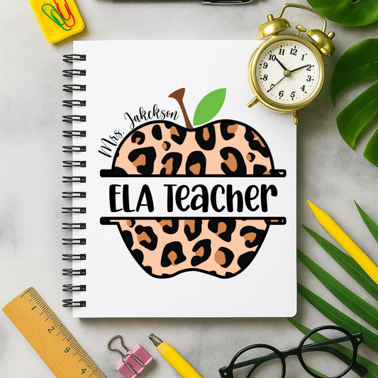 Notebook with leopard print apple design labeled 'ELA Teacher' on a desk with stationery items.