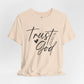 Beige t-shirt with 'Trust God' text on a light gray background